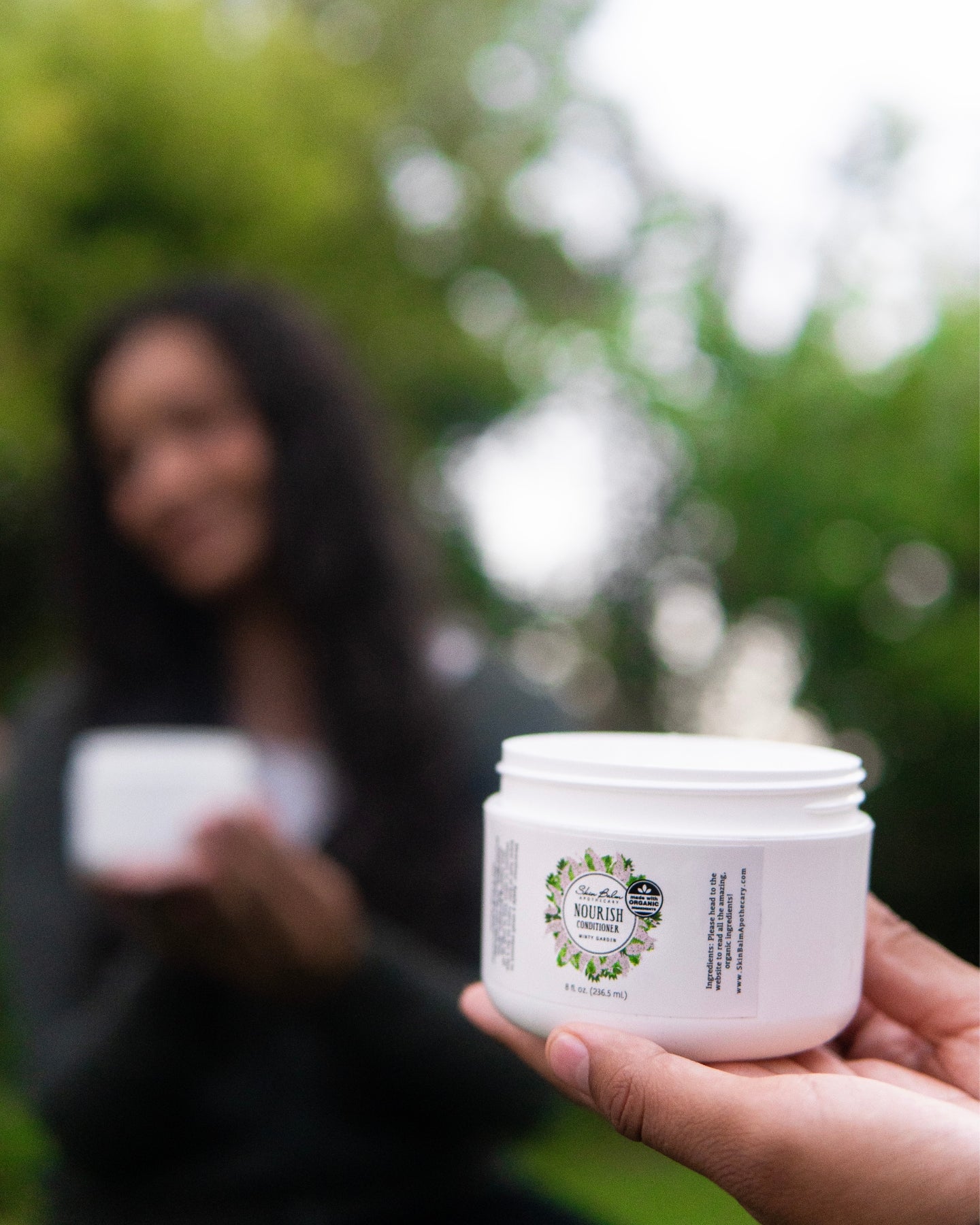 A close-up shot of the Minty Garden Nourish Conditioner resting on a woman's palm.